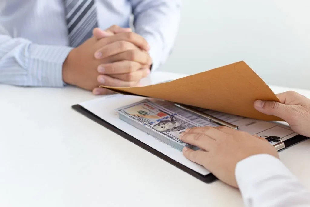 Remise d'une enveloppe contenant des billets, illustrant un risque de corruption en entreprise