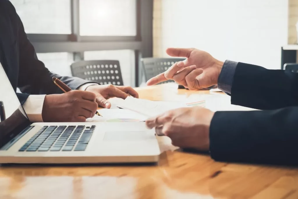 Deux professionnels échangeant des documents et graphiques lors d'un rendez vous de conseil en conformité
